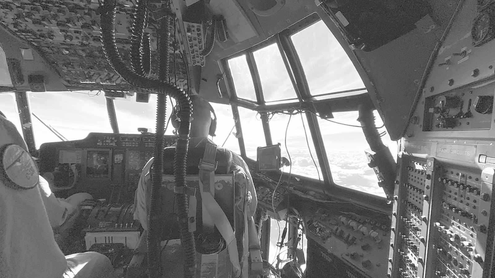 Flight deck of a C-130 Hercules in cruise, horizon and cloud deck visible through the windscreen