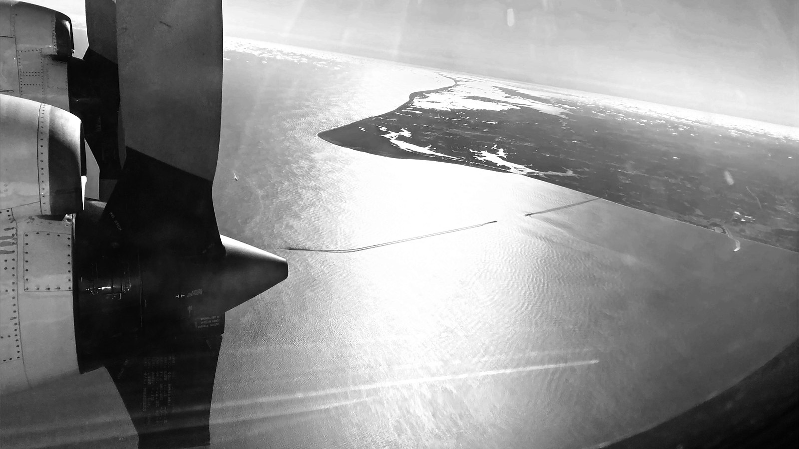 View from a P-3 Orion in flight, turboprop and wing over a coastline